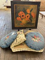 Front angle of folding table showing floral painted top and cushions piled in front