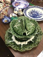 Table display of the pottery collection highlighting the green marble apple set, Delft plates, and smaller pottery pieces.