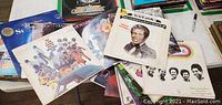 Overview of multiple vintage vinyl album covers on table, showing some titles and various artists