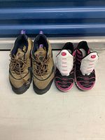 Top view showing two pairs of running shoes: brown/black Nike sneakers and pink/black Nike Air Max