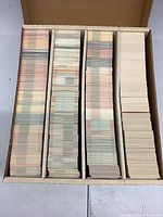 Four long stacks of trading cards in a box showing various card back colors and designs indicating assorted sports cards.