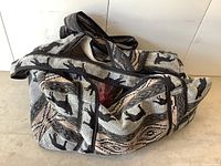 Woven fabric bag with cat silhouette designs in black, white, gray, and beige tones, used to hold costume jewelry items.
