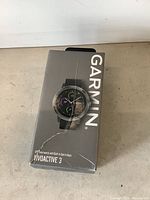 Box of Garmin Vivoactive 3 GPS smartwatch showing front with black band image and Garmin branding.