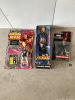 Photo of three Marvel action figures: Iron Man Spider-Woman in pink wings, Captain America in box, Spider-Man Noir in packaging.