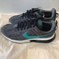Side view of the left and right Nike running shoes showing the patterned upper, turquoise swoosh, black laces, and white sole.