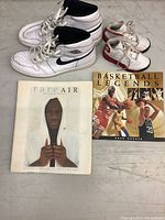 Photo shows two pairs of Air Jordan shoes next to two Michael Jordan biography books on a floor.