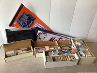 Overall view of multiple boxes filled with baseball and hockey cards plus two sports pennants for the Charlotte Bobcats and New York Mets.