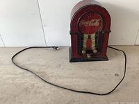 Full view of the vintage Coca-Cola clock showing its shape, power cord, and overall condition.