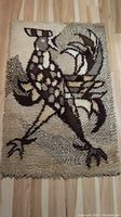 Full view of rectangular shag rug with stylized rooster design in brown and neutral tones on wood floor.