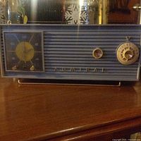 Front view of vintage Admiral clock radio showing yellow clock dial and tuning dial on grey textured front panel.