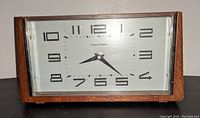 Front view of the Thomas O'Brien vintage desk clock showing the silver face with black numbers and hands inside a rectangular wooden case.