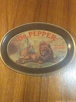 Front side of oval small metal serving tray showing vintage Dr. Pepper advertisement featuring a lion and red text.