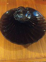 Top view of the black ceramic shell-shaped chip and dip bowl, showing the smaller dip bowl nestled inside the larger shell bowl.