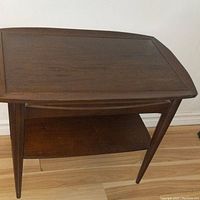 Front and top angled view showing the walnut tabletop with slight marks and tapered legs.