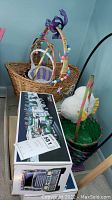 Photo shows wicker Easter baskets with colorful decorations alongside two boxed Hess toy trucks.