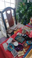 Wide view of the table showing colorful beaded necklaces, various chains, pins, small bags, and hats in background