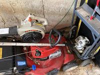 Overview photo showing both an Echo ES2100 blower and an Echo GT-200R string trimmer partially resting on a red lawn mower. Items show dust and dirt residue.