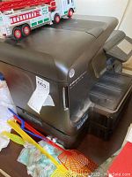 Side view of HP OfficeJet Pro 8600 Premium printer with Hess fire truck toy on top, showing printer's condition and fire truck details.