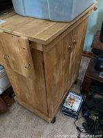 Side and top view of wood kitchen utility cart showing surface scratches and marks, with two doors and round wooden knobs, plus side hooks.