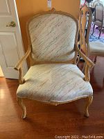 Front view of pickled pine upholstered armchair showing detailed carved wooden arms and back frame with abstract patterned fabric on seat and back