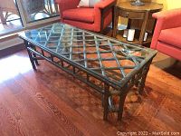 Front angle view of the cane frame coffee table with glass top showing lattice design and leg structure.