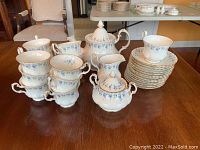 Teapot, sugar bowl, creamer, stacked teacups and saucers displayed on table