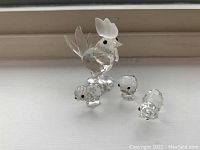 Front view of Swarovski hen with three chicks, showcasing the faceted clear crystal bodies and detailed frosted comb on hen.