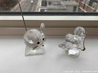 Photo showing both Swarovski crystal mouse and butterfly figurines on a window sill with urban background.