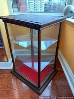 Front three-quarter view of the cabinet showing wood frame, glass sides and interior shelves