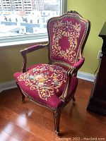 Front view showing burgundy needlepoint upholstery and carved crest