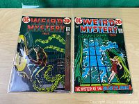 Two Weird Mystery comic book issues, #3 and #4, shown side by side on a wood surface with visible cover art.