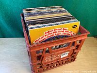 Red plastic Dominion Dairy milk crate filled with vinyl LPs