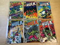 Top view of six Incredible Hulk comic books laid out showing front covers with bright colorful artwork primarily featuring Hulk in action.