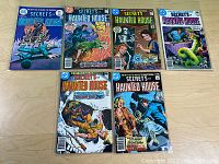 All seven comic book covers laid out on wooden floor showing titles and cover art.