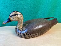 Side angle view of wooden duck decoy showing hand-painted feather details and black beak.