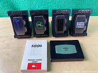 Four Zippo Greenskeeper pocket knives in original black blister packs with company logos visible on the metal brushed finish knives. Also General Tire branded pocket knife in black box with white outer box labeled Zippo.