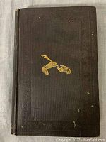 Front cover of cloth hardcover binding, embossed border and gilt pointing hands graphic. Shows some surface wear and small chips.