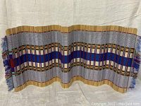 Full view of the woven bamboo table runner showing its length and color pattern with fringed edges, laid against a neutral background.