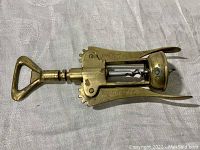 Top view of brass wing corkscrew wine opener lying flat showing handle and corkscrew shaft.