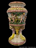 Front view of Capodimonte footed vase showing cherubs and pedestal footed base with yellow claw feet painted detail