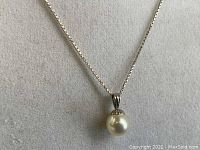 Close-up front view showing the pearl and pendant setting on the chain.