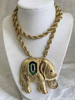 Front view of the necklace showing the large gold-tone elephant pendant with blue and green enamel decoration on the side, hanging on a thick twisted chain.