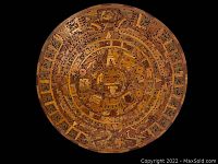 Close-up front view of the round carved wooden Mayan calendar showing detailed glyphs and central figure.