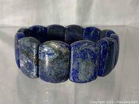 Photo of the rectangular Lapis Lazuli stones forming a wide cuff bracelet, showing color variation of deep blue with grey matrix.