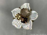 Top view showing flower-shaped ring with mother of pearl petals and four center stones (quartz, citrine, smoky topaz).