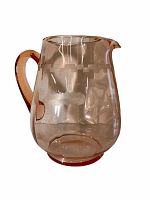 Side view of pink depression glass pitcher showing etched floral and geometric design and handle.