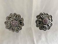 Front view of the pair of Judith Ripka sterling silver flower clip-on earrings showing floral design and pave CZ center.