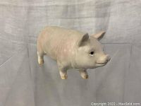 Overall side profile of the ceramic pig statue showing body shape and coloring.
