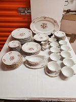 Photo showing entire 75-piece Walbrzycw china set arranged on a white tablecloth, including plates, bowls, gravy boat, creamer, teacups, saucers, and platter.