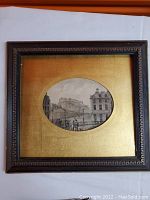 Framed artwork showing black wood frame with decorative edge and gold matte with oval opening for print